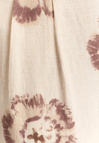 Blomtryckt tyg med krämfärgad bas och mörk vinröda accenter, med en strukturerad väv och plisserad detalj.