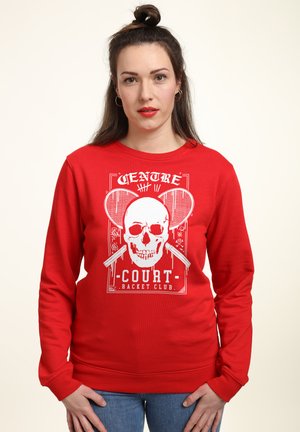Felpa rossa in cotone, con un design grafico di un teschio accompagnato da racchette da tennis. Polsini e orlo a costine, vestibilità rilassata.