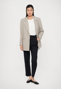 Light gray textured blazer over a white top, paired with black pinstriped trousers and black flats. The blazer features a relaxed fit.