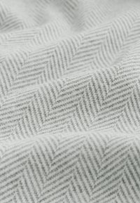 Tejido de patrón de espiga gris con textura sutil, que presenta franjas alternas de tonos claros y oscuros. Material suave y tejido.