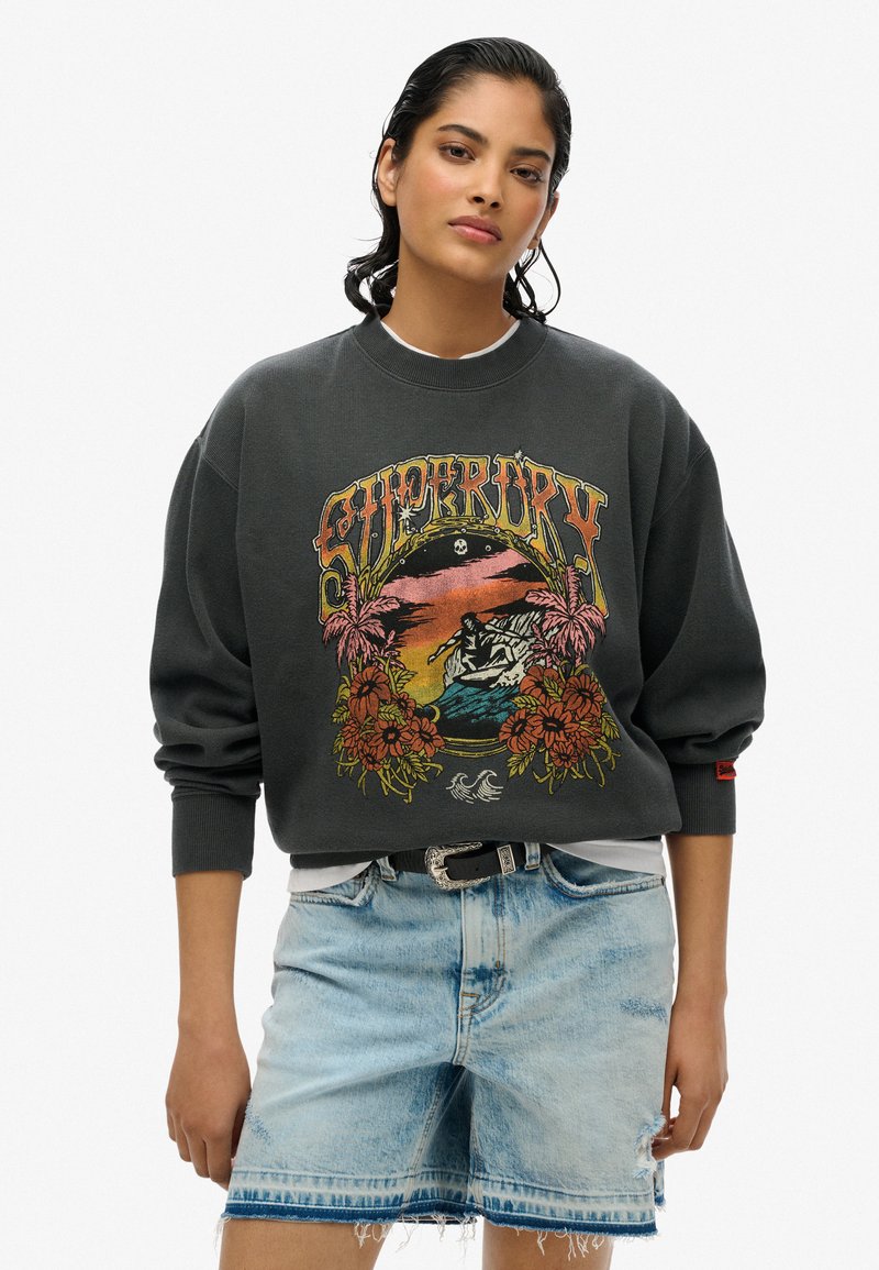 Grijze sweatshirt met een kleurrijk grafisch ontwerp van een strandscène met bloemen. Lichtblauwe versleten denim shorts met een rafelige zoom.