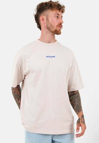 Camiseta de algodón de corte suelto en color rosa pastel, con escote redondo y mangas cortas; presenta el logotipo azul "SIXTH JUNE" en el pecho.