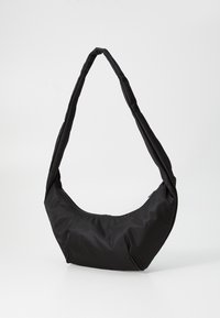 Borsa a spalla nera realizzata in tessuto morbido, con un design curvo e una sola tracolla spessa. Include una chiusura con zip nella parte superiore.