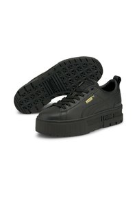 Baskets en cuir noir avec une semelle épaisse, présentant une semelle texturée, un système de laçage proéminent et un logo en accent doré.