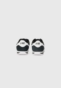 Nike tenisice s crno-bijelom shemom boja, od mrežaste i antilop kože, s udobnom potplatom i detaljima logotipa straga.
