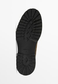 Semelle de chaussure en caoutchouc noir avec des profondeurs marquées, présentant un motif en diamant et un léger arc. Marquée "Massimo Dutti" et taille "42."