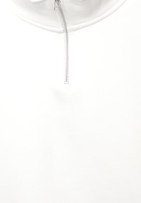 Wit kledingstuk met een zilveren rits die gedeeltelijk is geopend vanaf een ronde halslijn.