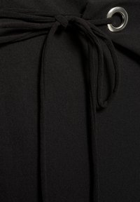 Fekete, sima textúrájú anyagban ez egy masni záródás, amit ezüst fém szemmel biztosítanak. A dizájn minimalista és letisztult.