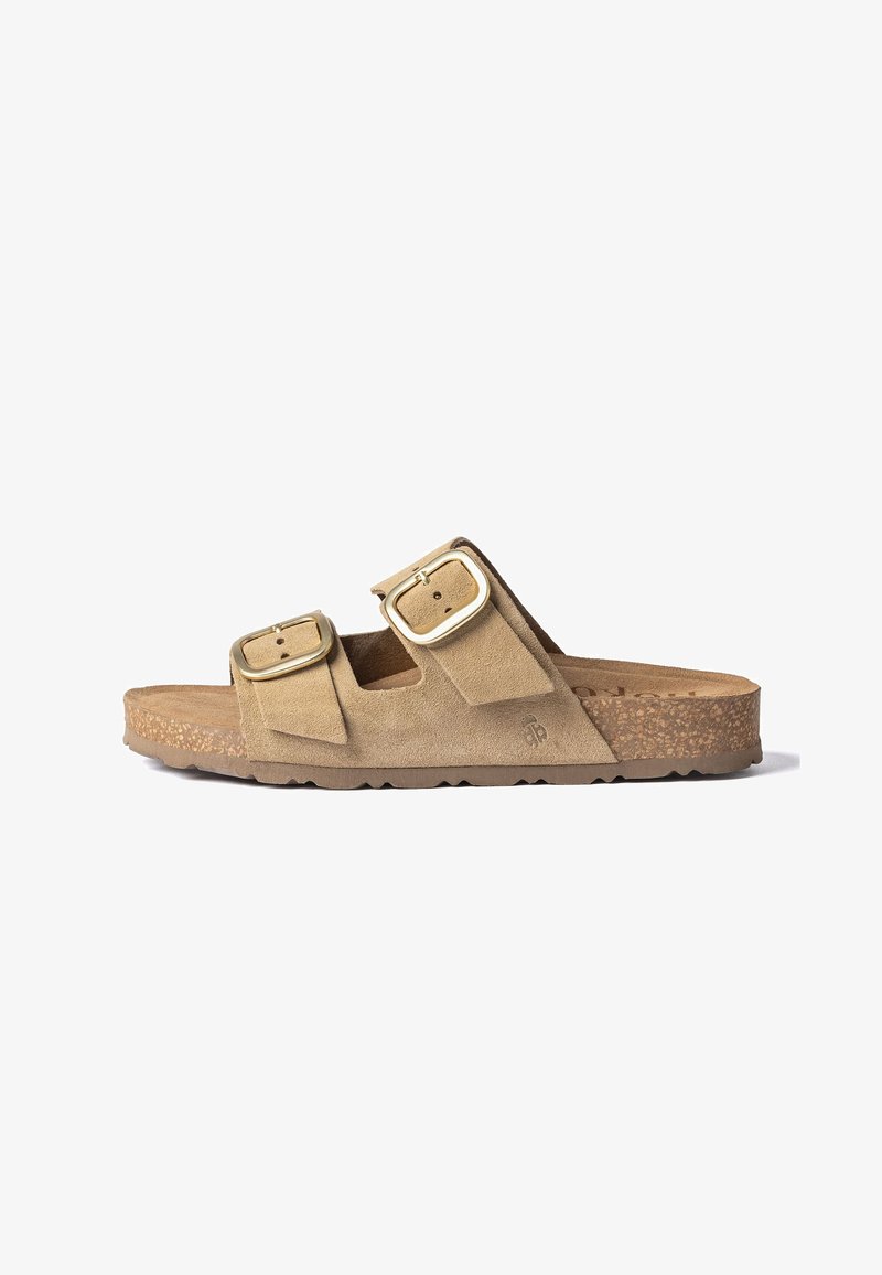 Beige suède slip-on sandaal met twee verstelbare gouden gespen, kurken voetbed en een gerubberde zool met reliëf, weergegeven in zijaanzicht.
