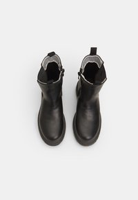 Črne usnjene gležnjarje z gladko površino, elastičnimi stranmi in zankami za obuvanje. Imajo rahlo zaobljen nos in teksturirano sivo podlogo.