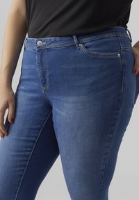 Blue jeans made of denim, featuring a classic five-pocket design, visible stitching, a mid-rise waist, and a slight fade on the fabric.