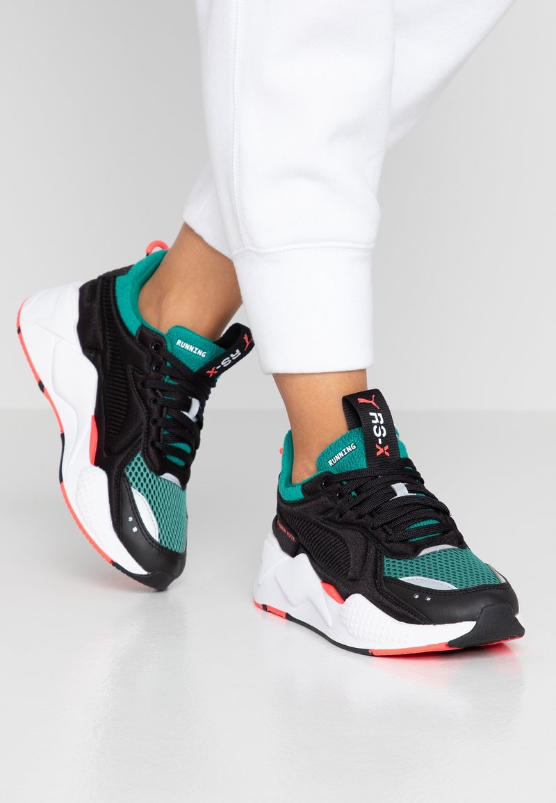 Svarta och teal sportiga sneakers i mesh och läder, med en djärv design, vit mellansula och rosa accenter.