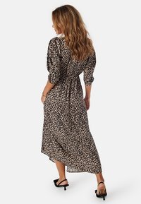 Leopardmönstrad maxiklänning med långa ärmar, smal midja och flytande nederkant. Tillverkad av lättviktsmaterial; har en avslappnad passform och rund halsringning.