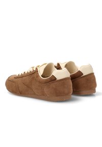 Zapatillas de ante marrón con acentos en crema, superficie texturizada, punta redondeada y suela plana de goma. Los cordones también son beiges para un aspecto cohesivo.