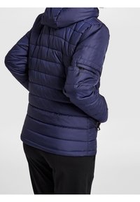 Chaqueta de plumas azul marino con capucha, con costuras horizontales y bolsillos laterales con cremallera. Tela suave y brillante con una textura blanda.