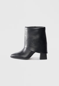 Black leather ankle boot with a pointed toe, smooth texture, and a structured block heel. Features a high, folded cuff design.