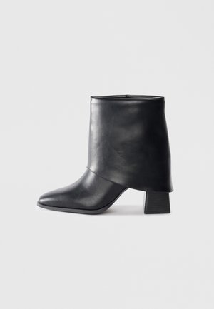 Black leather ankle boot with a pointed toe, smooth texture, and a structured block heel. Features a high, folded cuff design.
