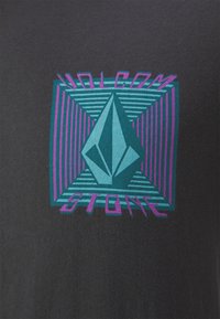 Camiseta negra con un diseño de logo geométrico en tonos verde azulado y púrpura, con el texto "VOLCOM" y "STONE" centrados dentro de un patrón de rayas.