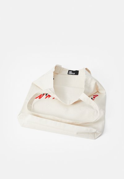 Geantă din pânză crem, cu eticheta albă "The Kooples" și un print de text roșu și negru parțial vizibil în interiorul genții.