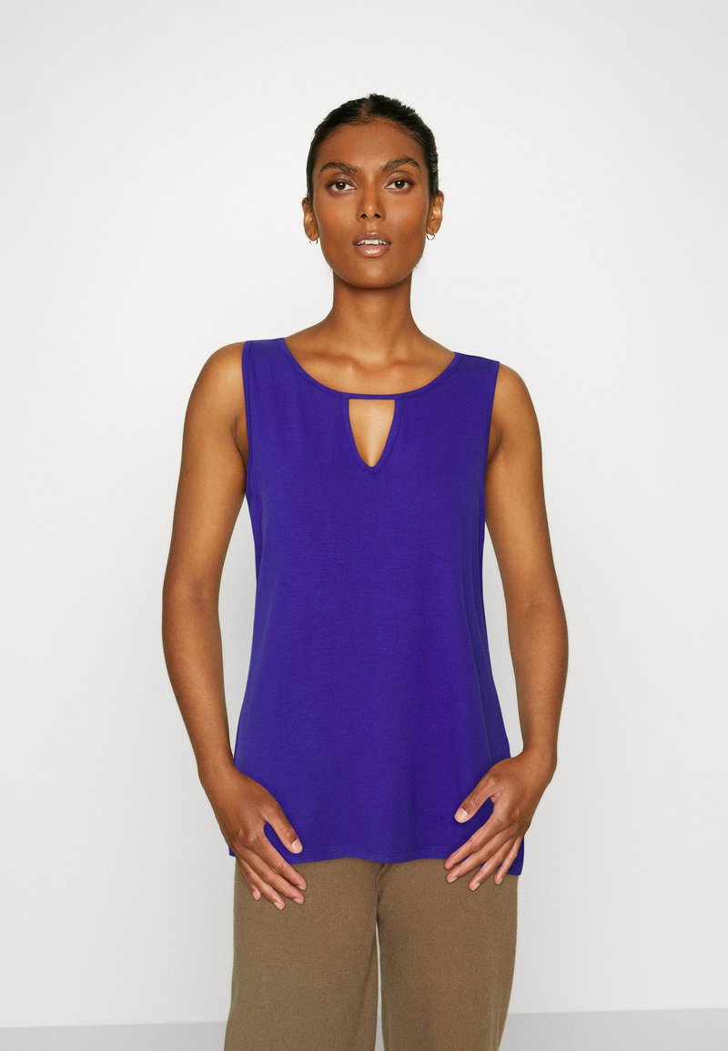 Top roxo sem mangas com um detalhe em forma de buraco na gola, feito de um tecido suave. O design apresenta um corte relaxado e uma bainha arredondada.