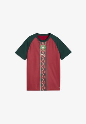 Maillot de football bordeaux avec manches et col vert foncé, bande centrale à motifs, et un logo circulaire vert au-dessus d'un logo Puma blanc.