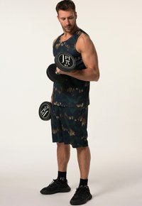 Completo da allenamento composto da un top senza maniche a motivo verde scuro e oro e pantaloni cargo coordinati; tiene due manubri neri, tessuto texturizzato.
