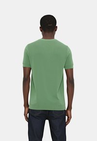 Maglietta verde a maniche corte in maglia realizzata in tessuto morbido, con scollatura rotonda e design aderente. Il retro è senza cuciture con una texture sottile.