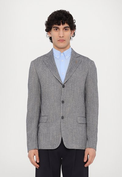 Grauer, strukturierten Blazer mit einem subtilen Streifenmuster, Ein-Knopf-Verschluss, Reverskragen und zwei Fronttaschen über einem hellblauen Hemd.