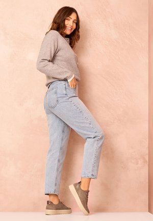 Hellblaue hochgeschnittene Jeans mit geradem Schnitt, kombiniert mit einem grauen Pullover und grauen Turnschuhen. Glatte Texturen und lässiges Design.