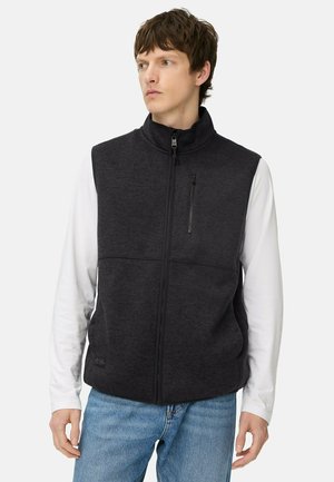 Schwarze Fleece-Weste mit hohem Kragen, Reißverschluss vorne und Brusttasche. Glatte Textur, seitliche Taschen und ein sauberes, modernes Design.
