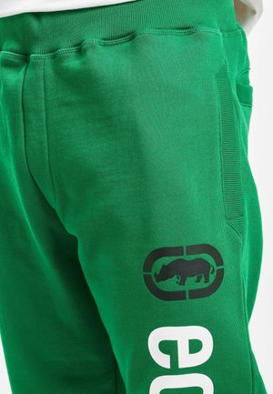Green sweatpants made of cotton blend material, featuring a black rhinoceros graphic and white lettering on the side. Elastic waistband included.