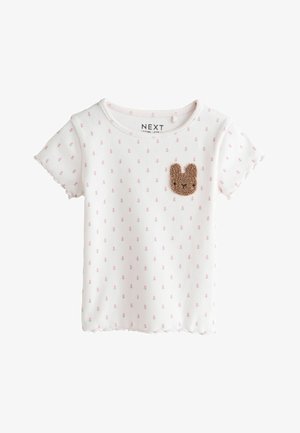 Biała bawełniana koszulka z krótkimi rękawami, ozdobiona różowymi groszkami i brązową naszywką z króliczkiem na piersi. Faliste brzegi.