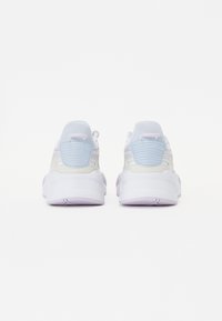 Witte en lichtblauwe sneakers met een paarse zool. Heeft textuuraccenten, een achterste trekband en pastelroze details. Rondvormig.
