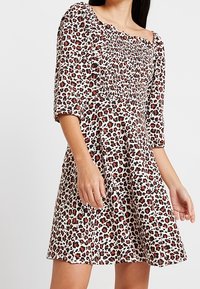 Šaty s leopardím vzorem, čtvercovým výstřihem, tříčtvrtečními rukávy a přiléhavým živůtkem, které přechází do rozšířené sukně. Měkká textura látky.