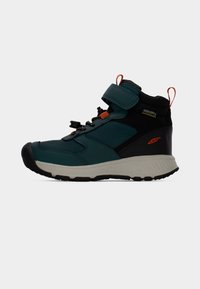 Το πεζοπορικό μποτάκι σε τιρκουάζ και μαύρο διαθέτει αδιάβροχο σχεδιασμό, ρυθμιζόμενο λουρί και υφή σε διάφορα σημεία, με ανθεκτική λαστιχένια σόλα.