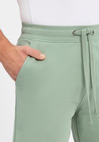 Mintgrüne Jogginghosen aus weichem Material, mit einem elastischen Bund und Kordelzug, seitlichen Taschen und einer glatten Textur.
