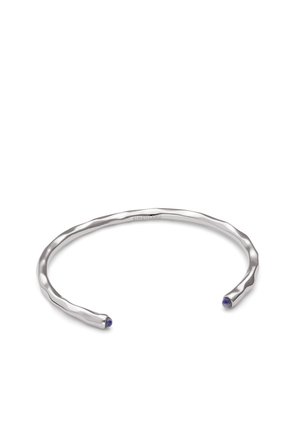 Pulsera de brazalete abierta de plata con una superficie texturizada y pequeñas piedras azules redondas colocadas en cada extremo.