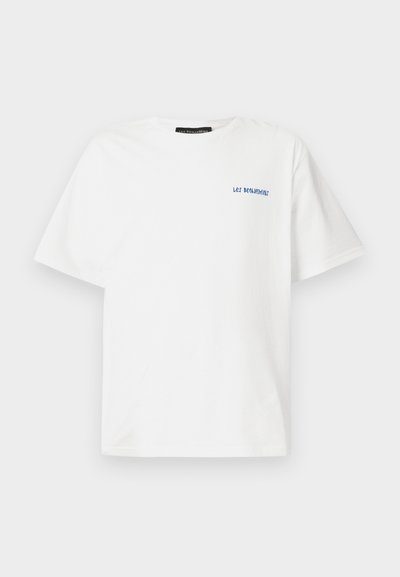Camiseta de algodón blanca de manga corta, con el texto azul "¡DEJA A BENJAMIN!" en el área del pecho izquierdo, diseño de cuello redondo estándar.