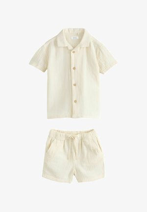 Kremowa koszula na krótki rękaw zapinana na guziki oraz pasujące szorty z elastycznym ściągaczem w talii, oba wykonane z lekkiego, teksturowanego materiału.