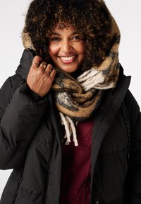 Zwarte pufferjack, dikke sjaal met een mix van bruin, zwart en crème tinten, met franjes. Warme, gezellige texturen en een snug fit.