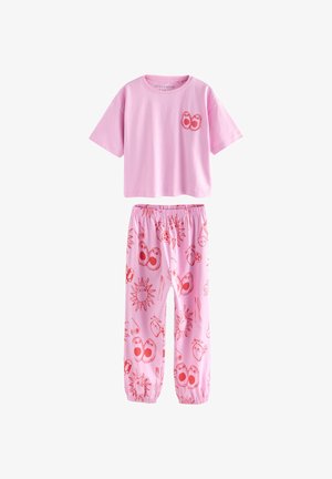 Rožinės medvilninės pižamos rinkinys, sudarytas iš trumpomis rankovėmis marškinėlių su grafine kišene ir pižamos kelnių su žaismingais saulės ir veido raštais.