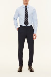 Blauw overhemd, marineblauwe pantalon en bruine leren schoenen. Het overhemd heeft een klassieke kraag; de stropdas heeft diagonale strepen.