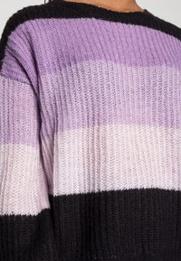 Maglione lavorato a maglia con righe orizzontali in tonalità di lavanda, rosa e nero. Presenta un colletto rotondo e un tessuto testurizzato.