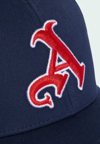 Námornícka modrá čiapka s výrazne vyšitou červenou literou "A" obrysom v bielej farbe. Textúra látky je hladká a má štruktúrovaný dizajn.