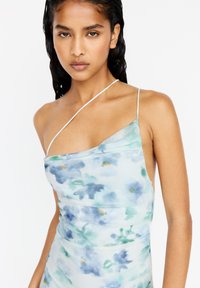Himmelblaues Kleid mit floralem Aquarellmuster, dünnen Spaghettiträgern und einem fallenden Design. Glatte Textur, figurbetonte Silhouette.