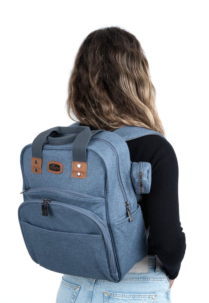 Blå tygryggsäck med bruna läderdetaljer, flera dragkedjefack, vadderade remmar och ett handtag på toppen; kompakt och strukturerad design.