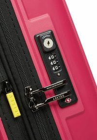 Maleta rígida rosa con candado de combinación, cremallera negra y tiradores de cremallera de metal. Marca Delsey en la lengüeta de la cremallera. Acabado texturizado.