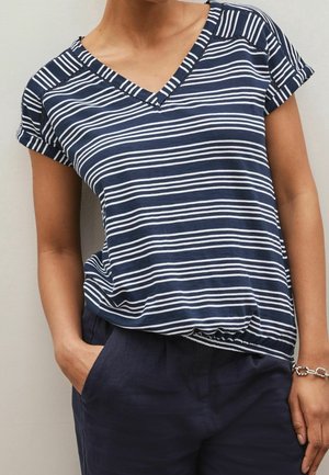 Navy blue short-sleeve top with white horizontal stripes, featuring a V-neck and a relaxed fit. Worn with dark navy pants and silver bracelet.