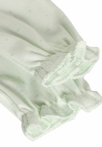 Ljust grönt stickat tyg med små blå prickar; elastiska volangärmar; mjuk textur med en slät yta.