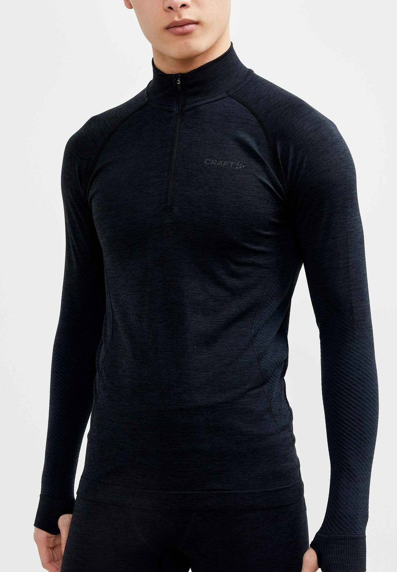 Zwart sportshirt met lange mouwen en een halve rits, gemaakt van rekbare stof, met ribbelaccenten op de mouwen en een logo op de borst.